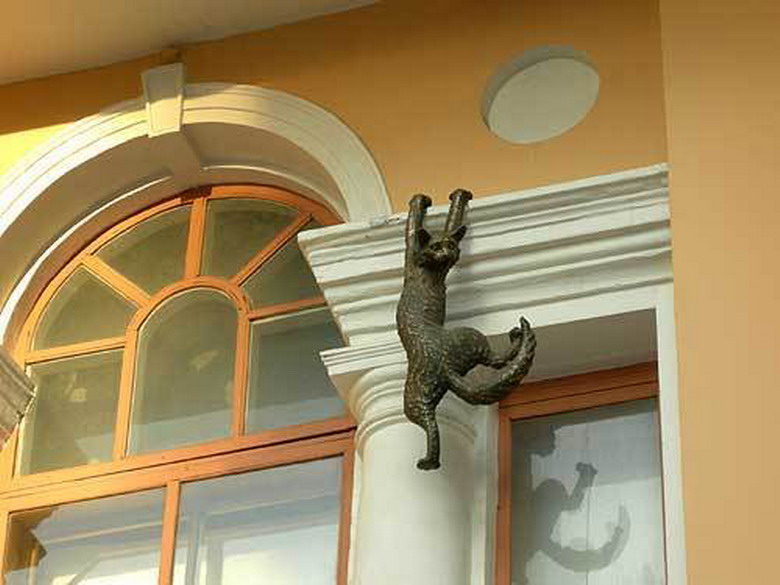 Кот на карнизе. Скульптура кошки. Кот висит. Кот на фасаде.