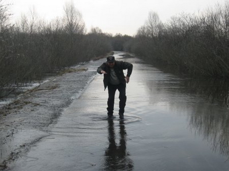 По колено. Мужчина идет по лужам. Лужи по колено. По колено в воде. Парень идет лужам.